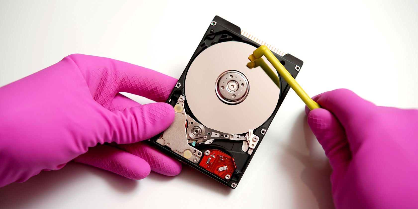 person scrubbing a hard drive disk with tiny brush feature