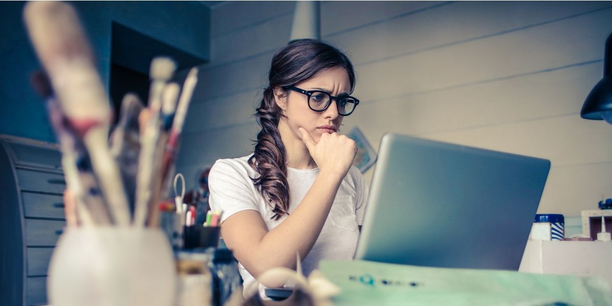 Photo of a woman thinking while looking at a laptop screen