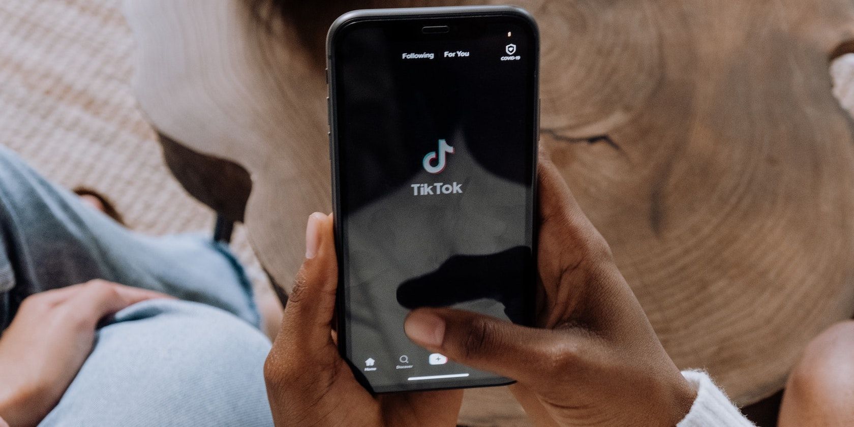 Hands holding a smartphone with the Tiktok logo on the screen