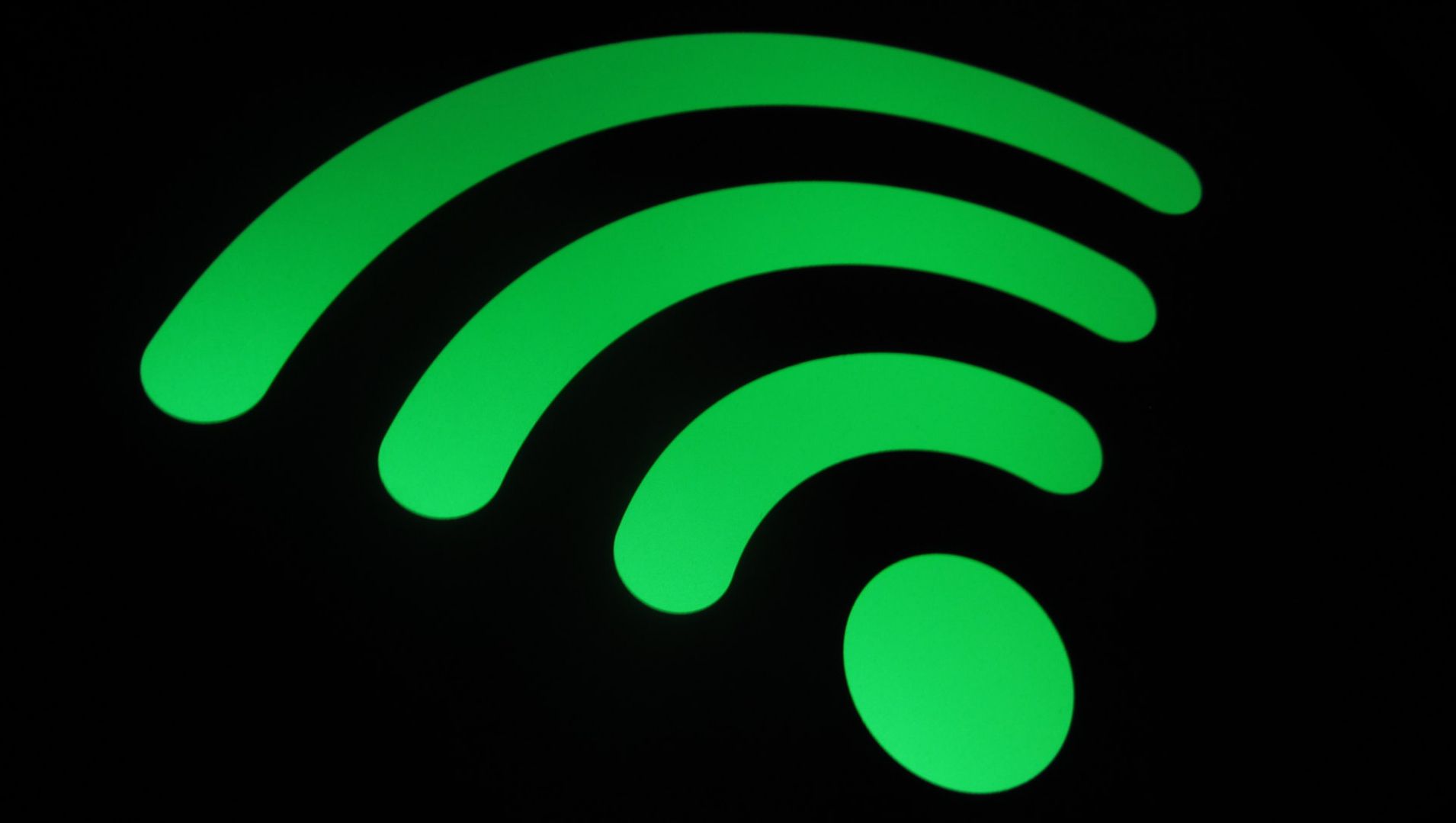 close up shot of green wifi logo on black background