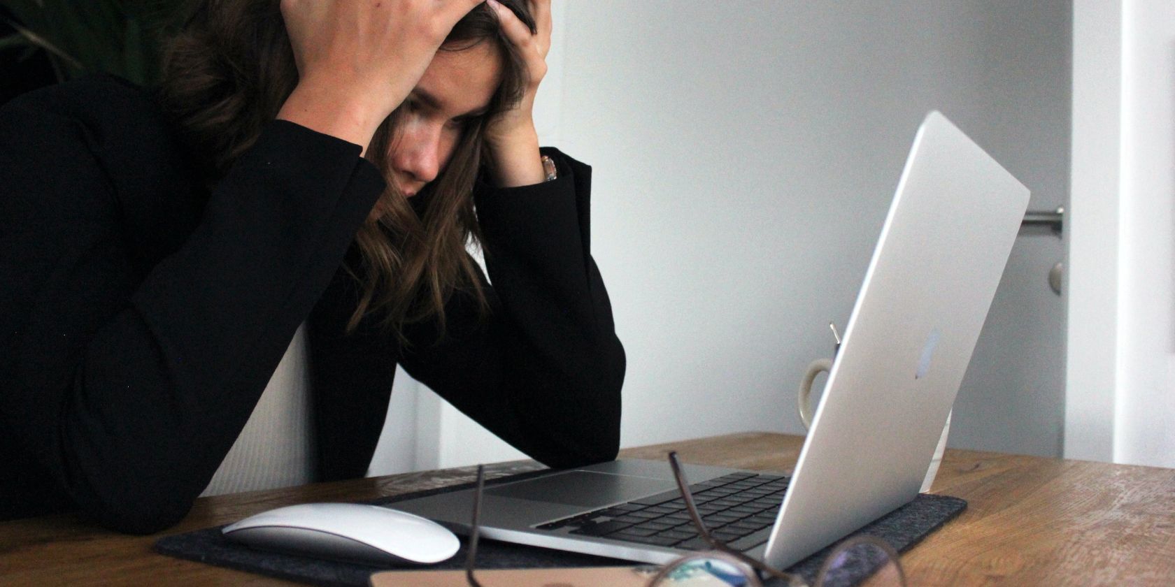 A woman stares at her laptop with her head in her hands, clearly frustrated