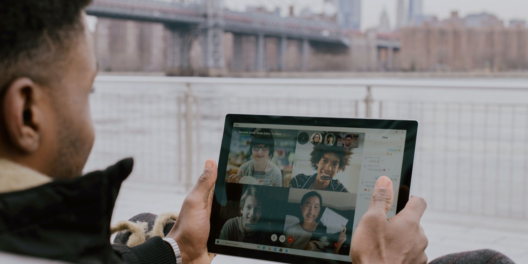 A man holding a Surface tablet and on a video call