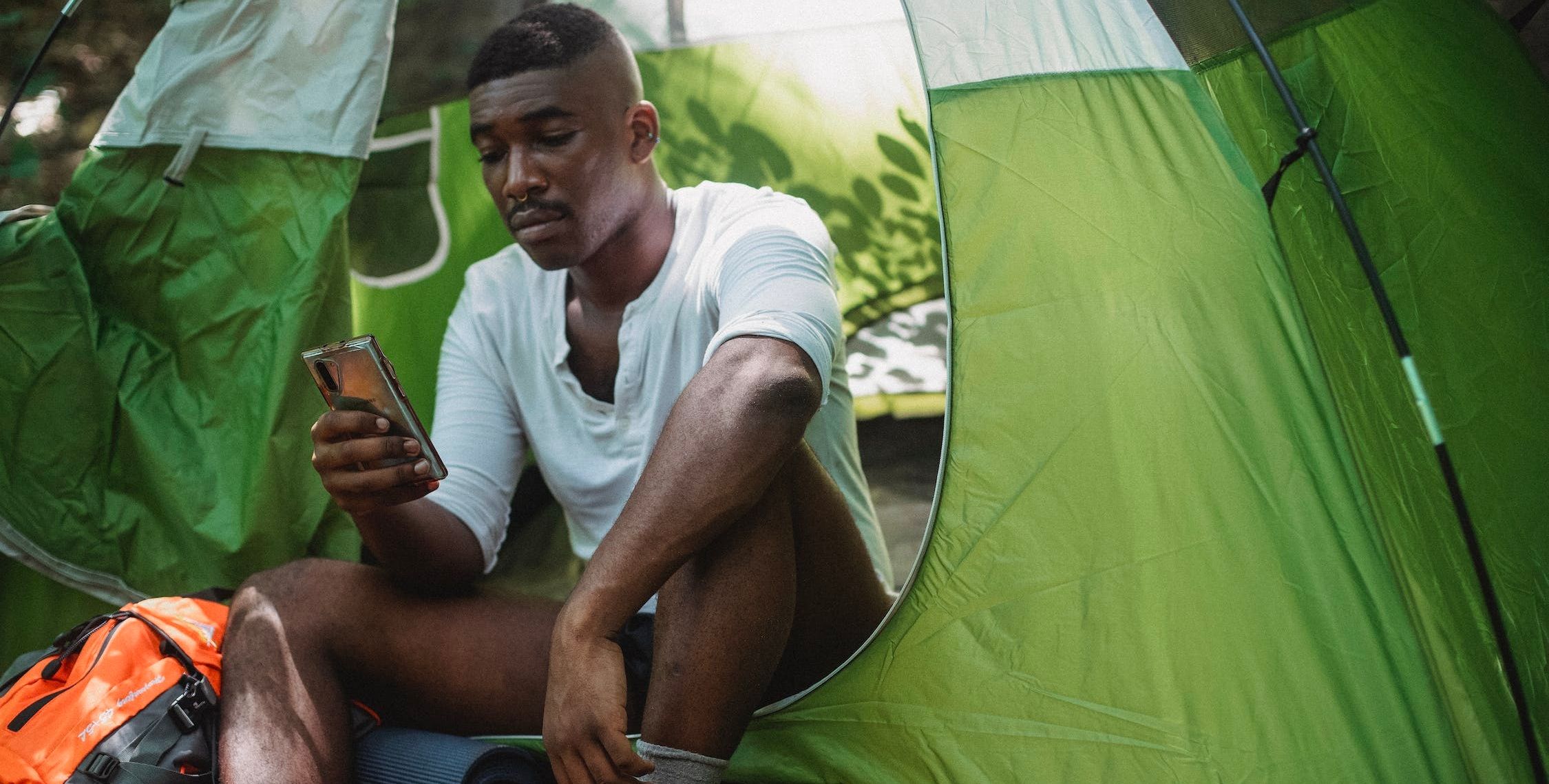 một người đàn ông ngồi trong lều cắm trại cầm điện thoại