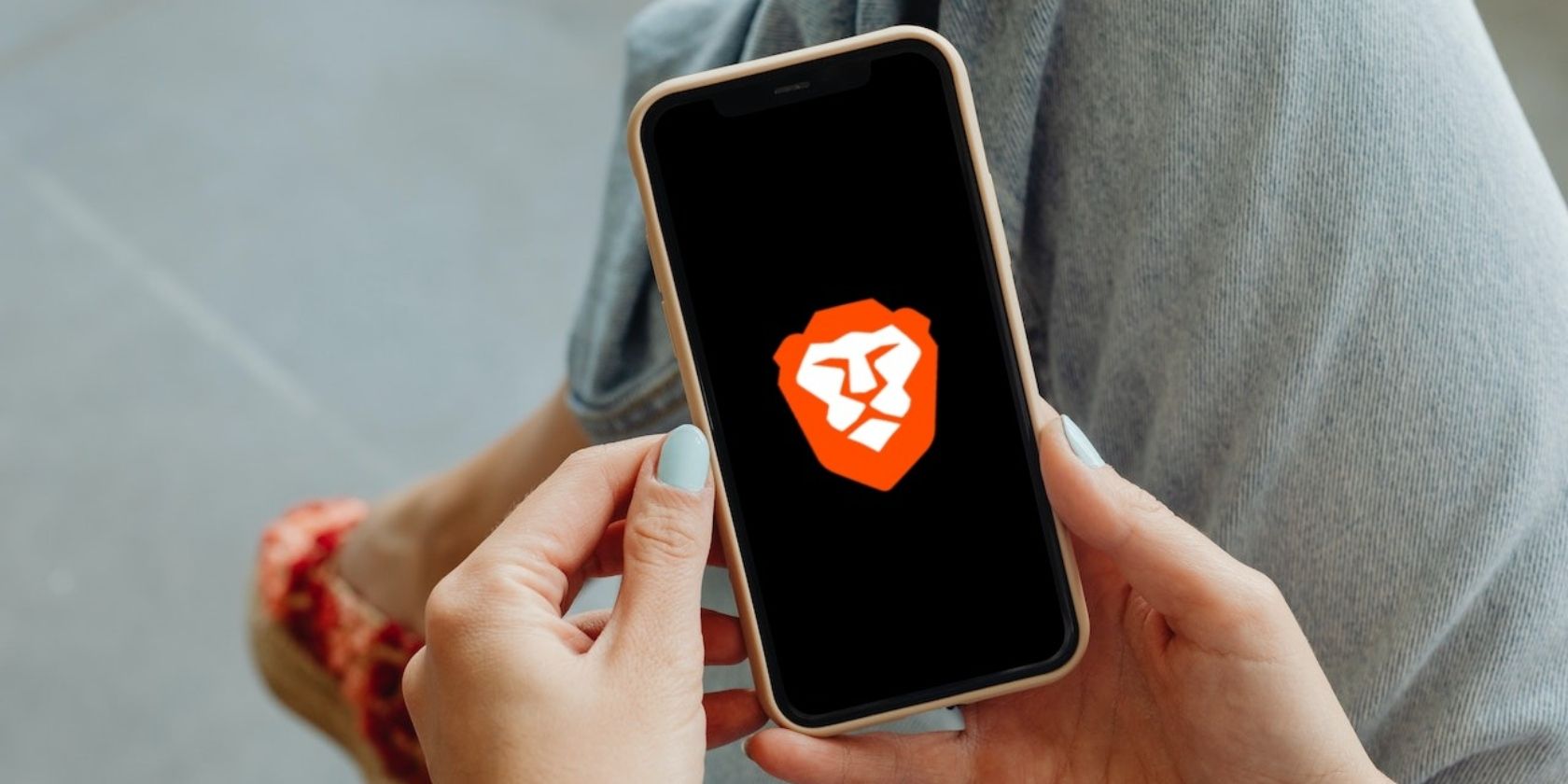 A woman holding an iPhone with the Brave logo on the screen-1