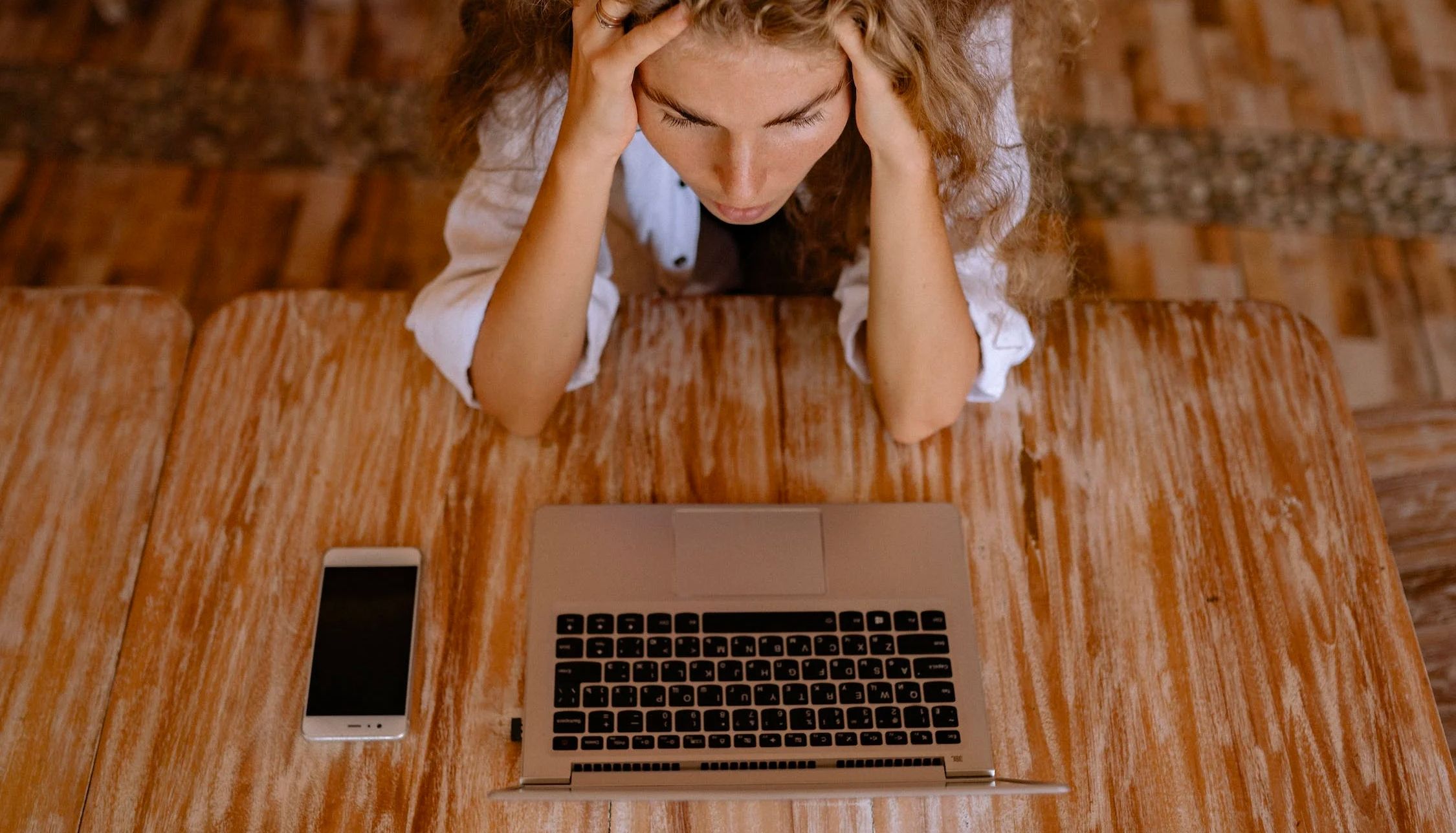 Một người phụ nữ đang ôm đầu khi nhìn chằm chằm vào màn hình MacBook