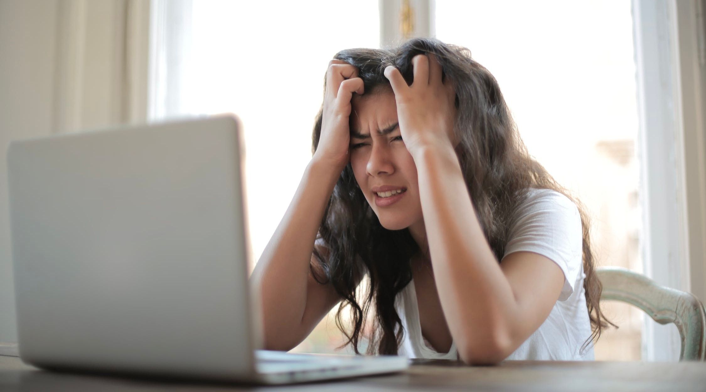 Một người phụ nữ ngồi trước máy tính xách tay ôm đầu thất vọng