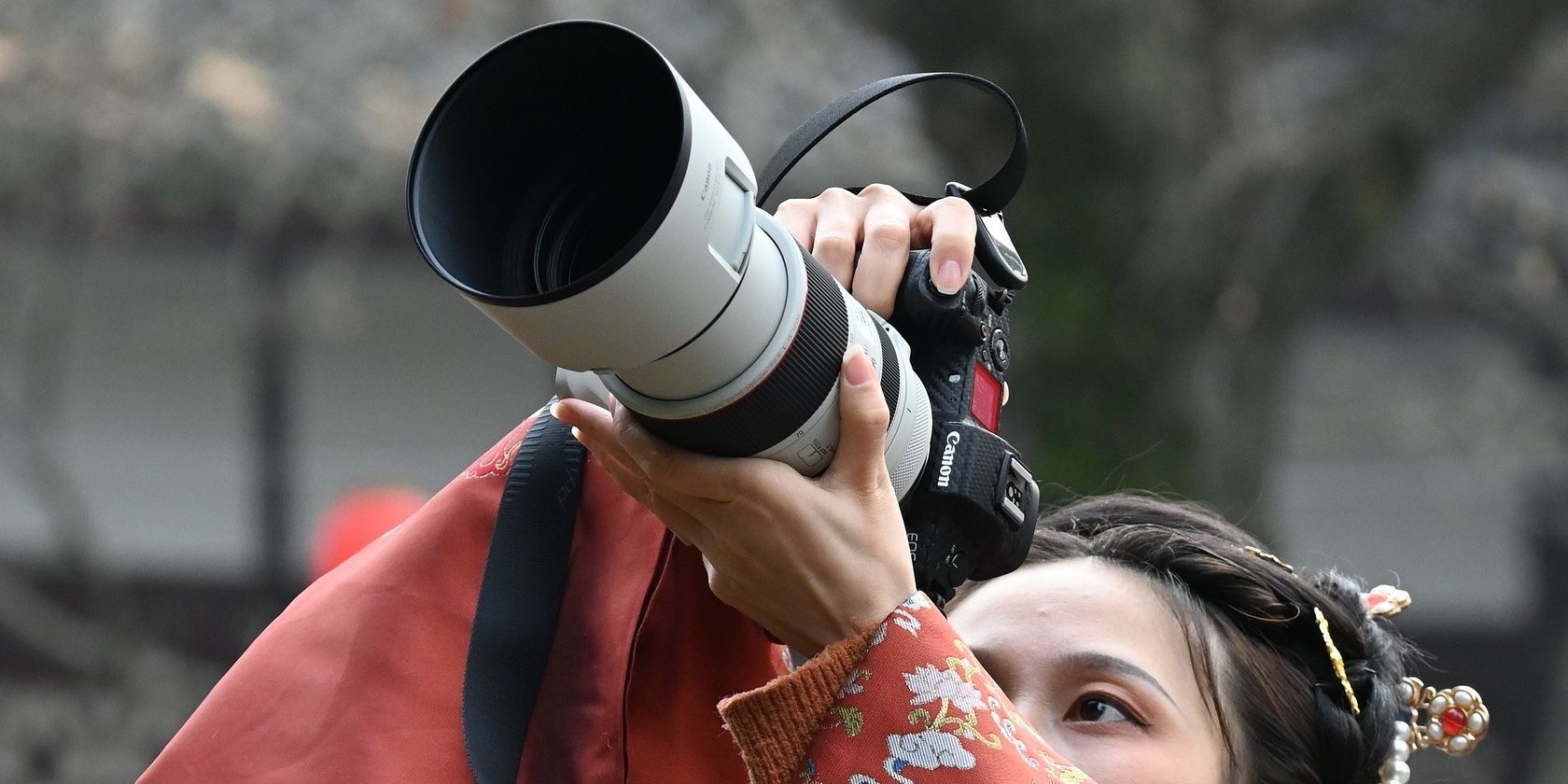 A woman holding a camera with a long telephoto lens