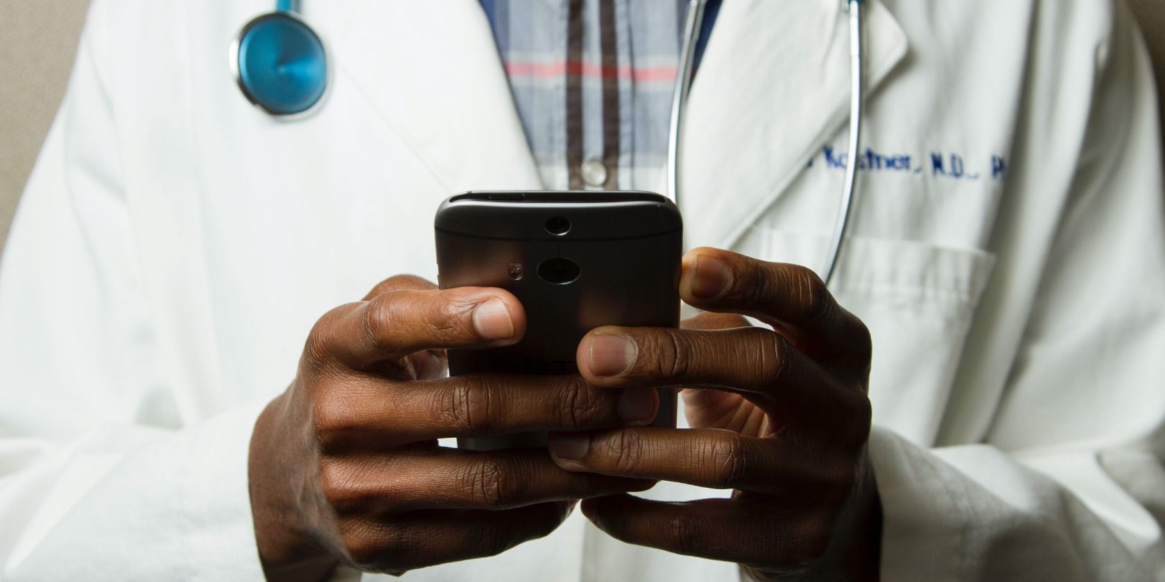 A doctor typing on a cell phone.