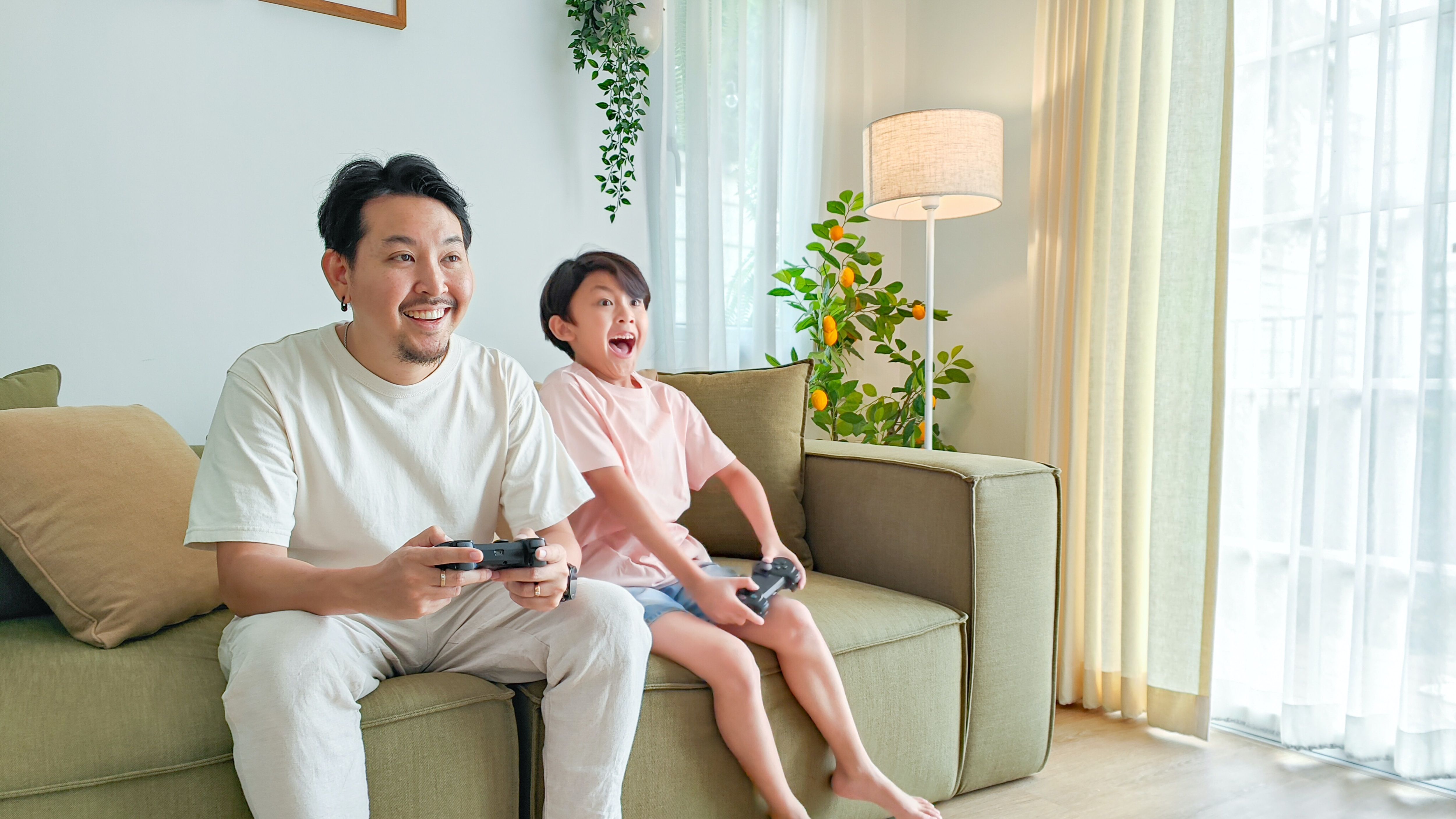   Một người cha và con trai đang chơi trò chơi điện tử trên đi văng