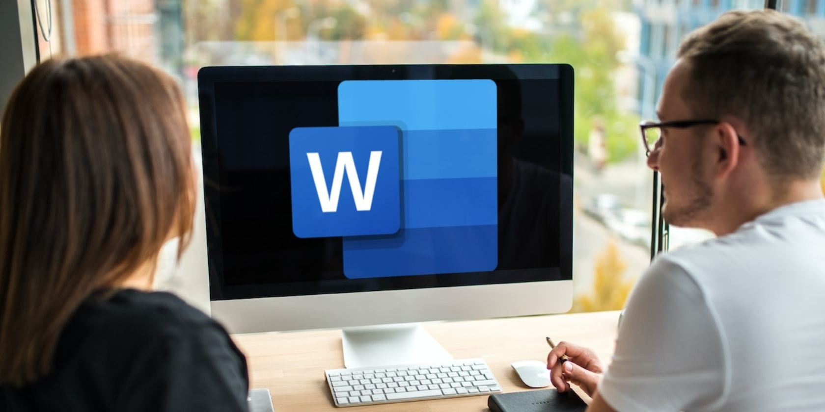 Logo Microsoft Word trên màn hình mac có hai người đang xem