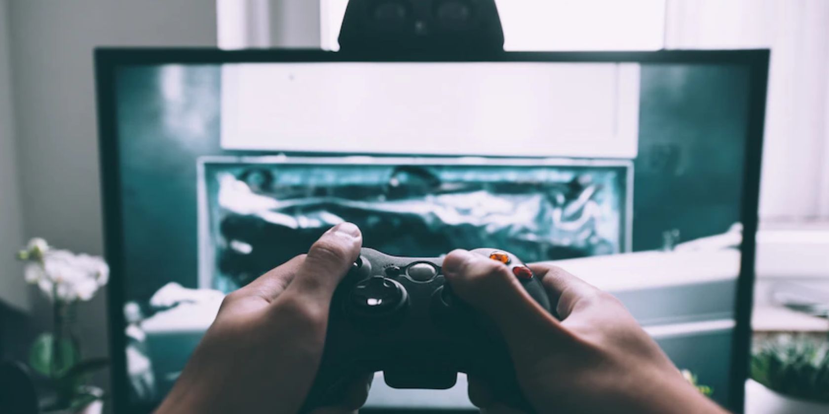 Monitor displaying a video game with hands holding a controller in front of the screen.
