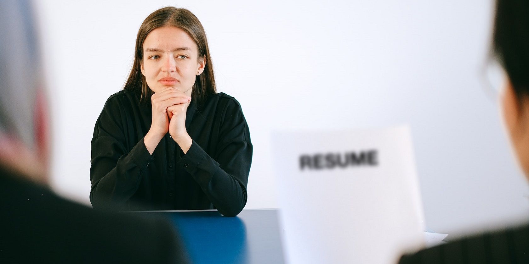 Image of a woman facing two people with one holding a resume