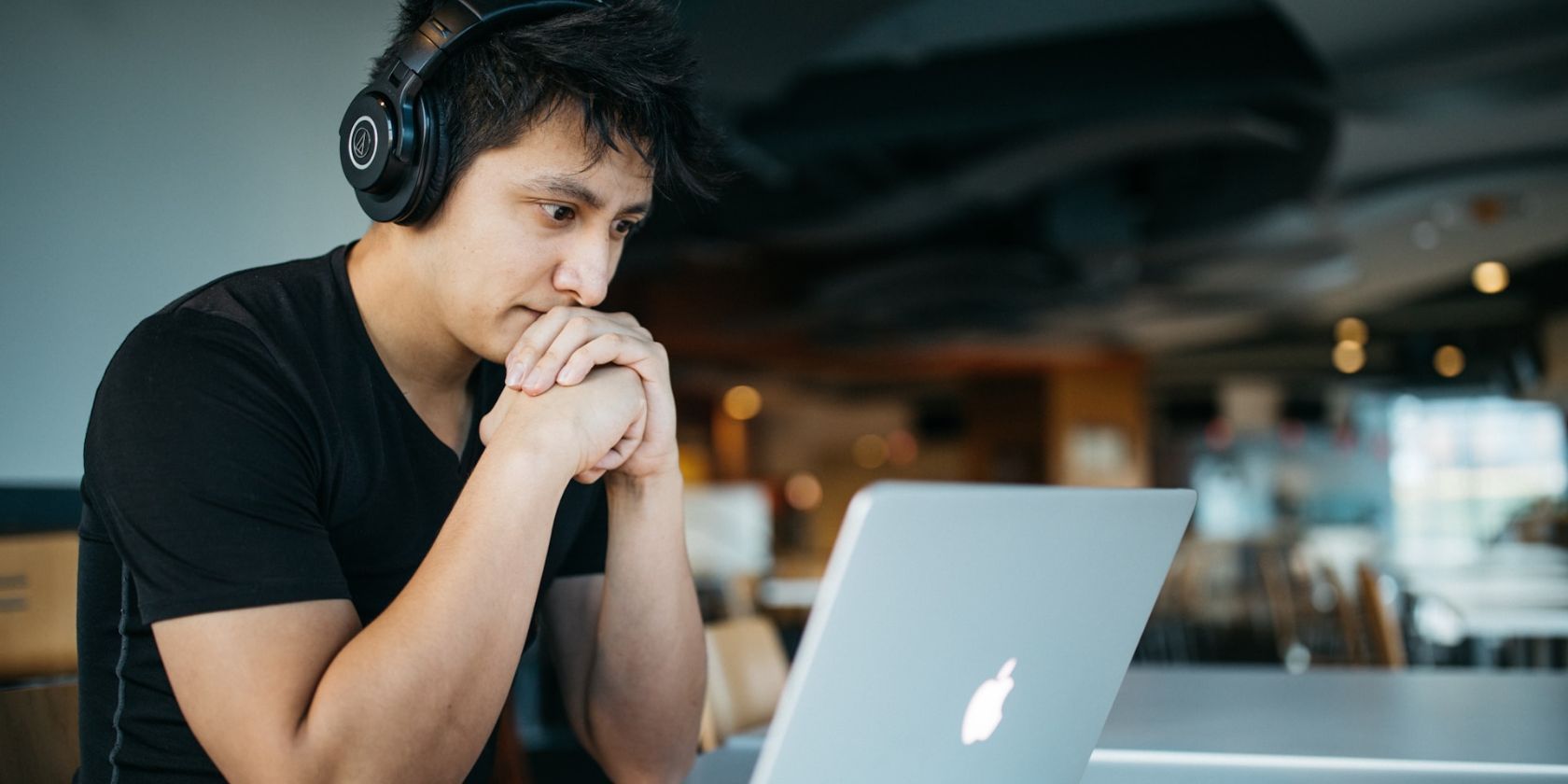 một người đàn ông đeo tai nghe ngồi trước máy tính xách tay