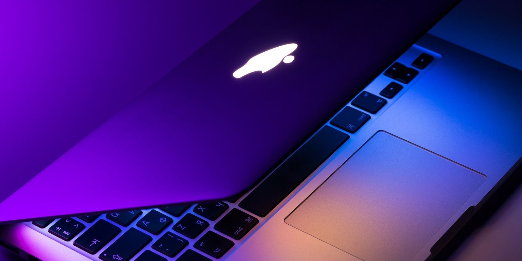 half open macbook under purple and pink light hue