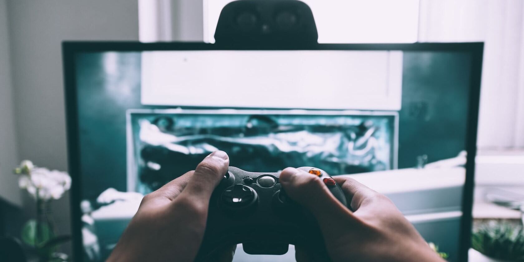Man holding a game controller in front of a monitor screen