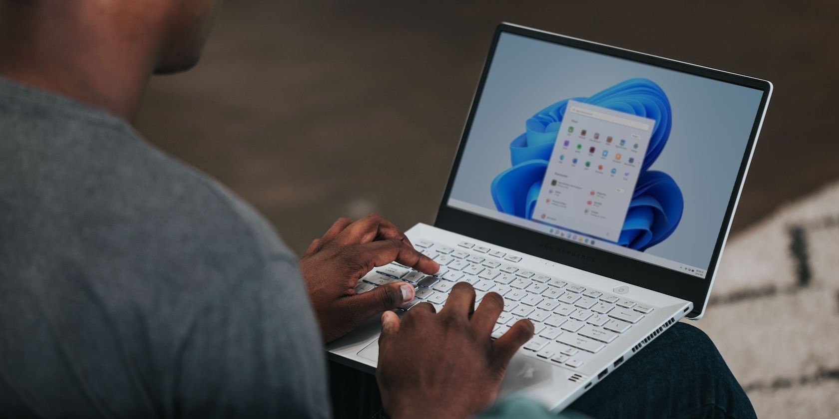 Man in gray shirt using Windows 11 laptop
