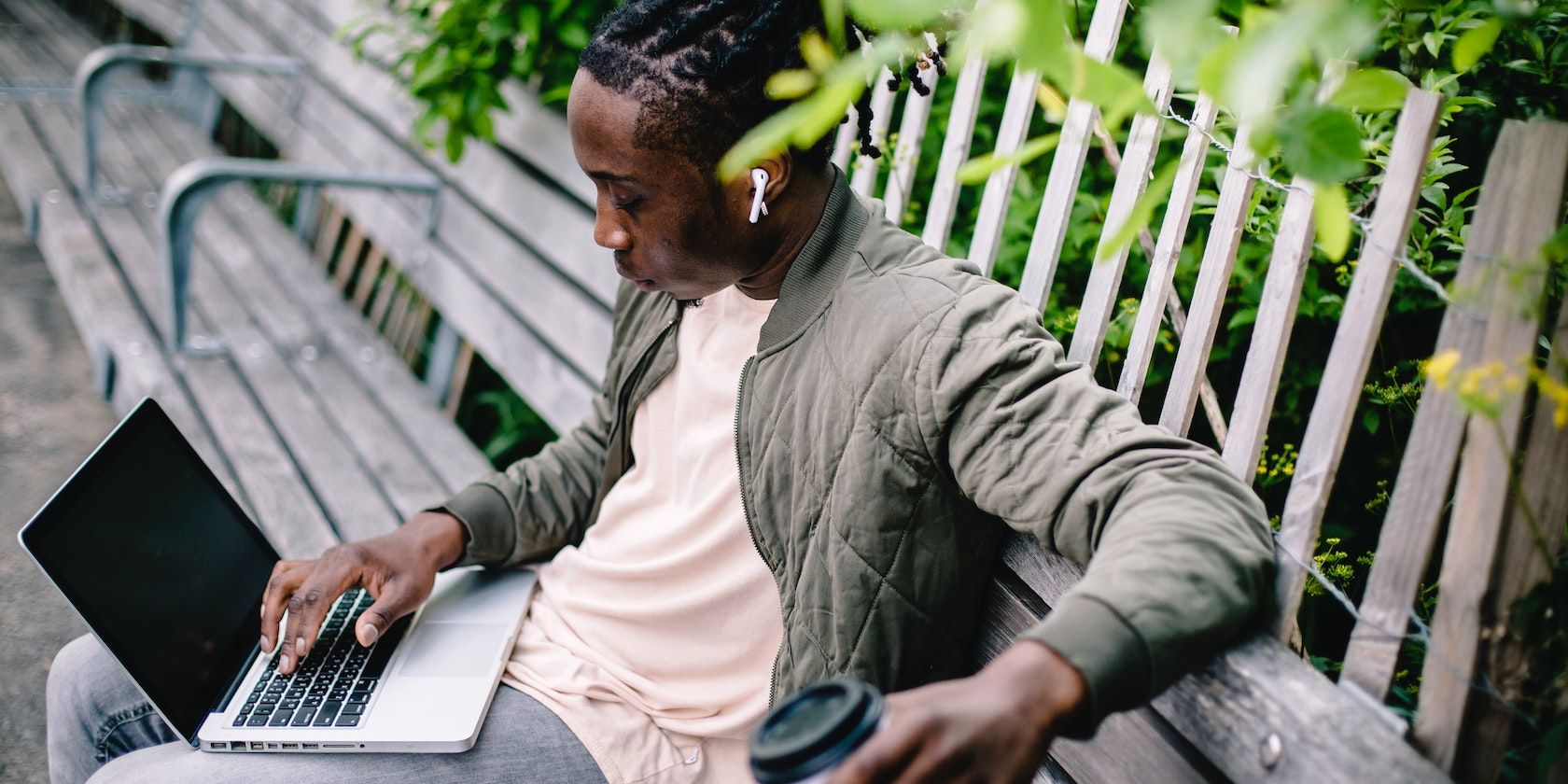 man wearing earbuds listens to music with laptop