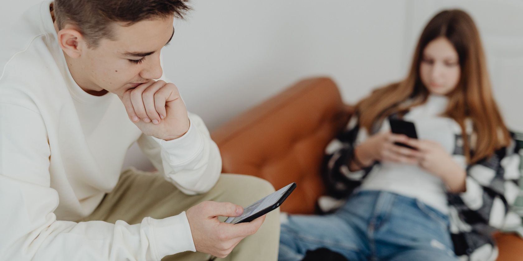 man and woman sitting on couch using smartphones