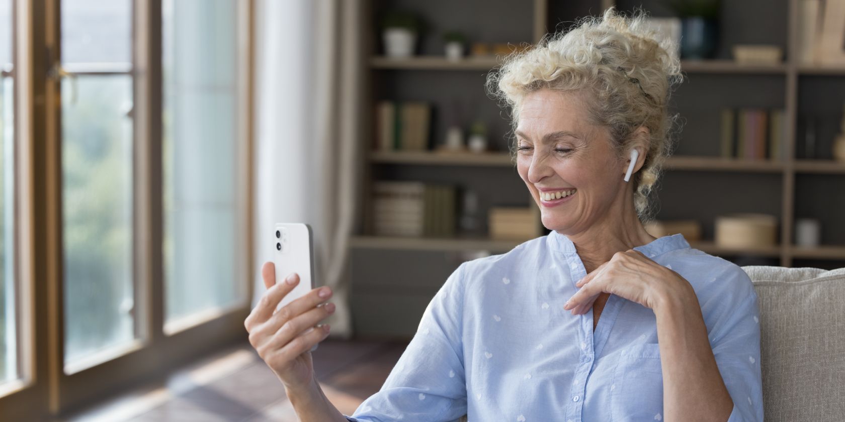 Elderly person wearing wireless headphones and video chatting on their phone