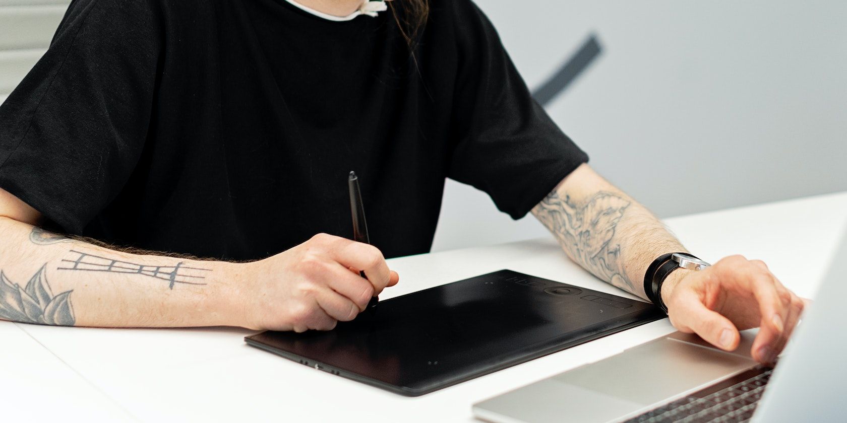 man uses a drawing tablet to illustrate on laptop