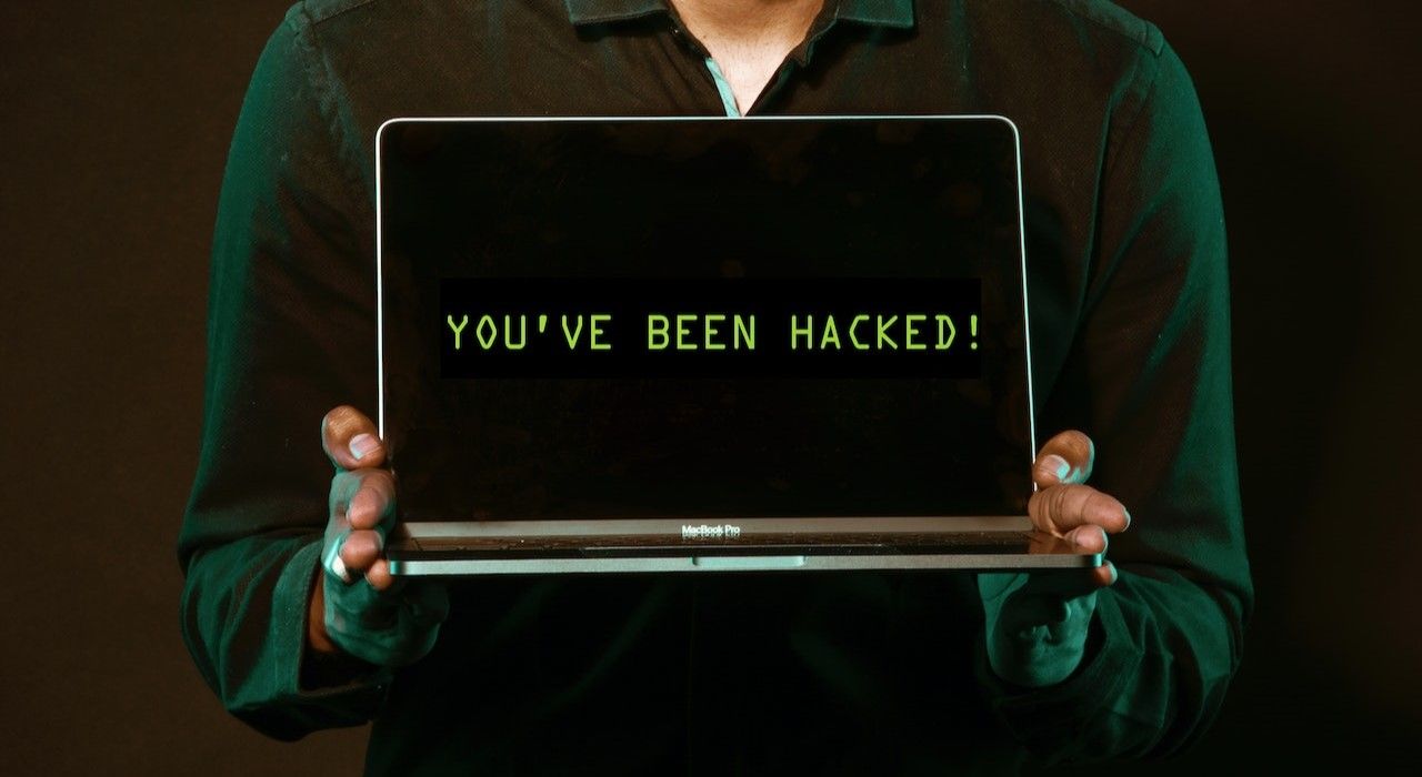 Photo of Person Holding a Laptop with Text You Have Been Hacked Written on Its Screen