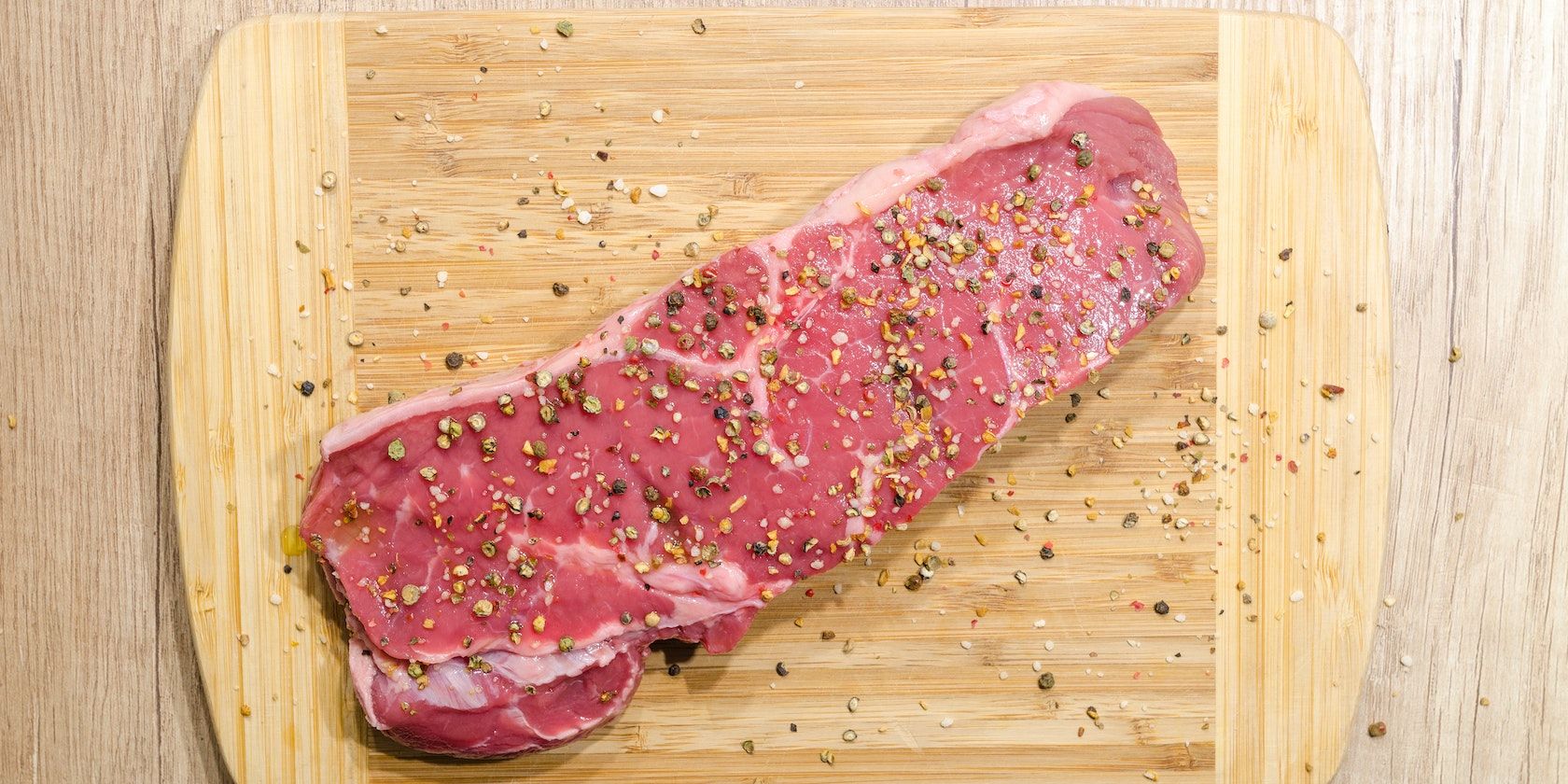 Piece of raw seasoned beef on a chopping board 
