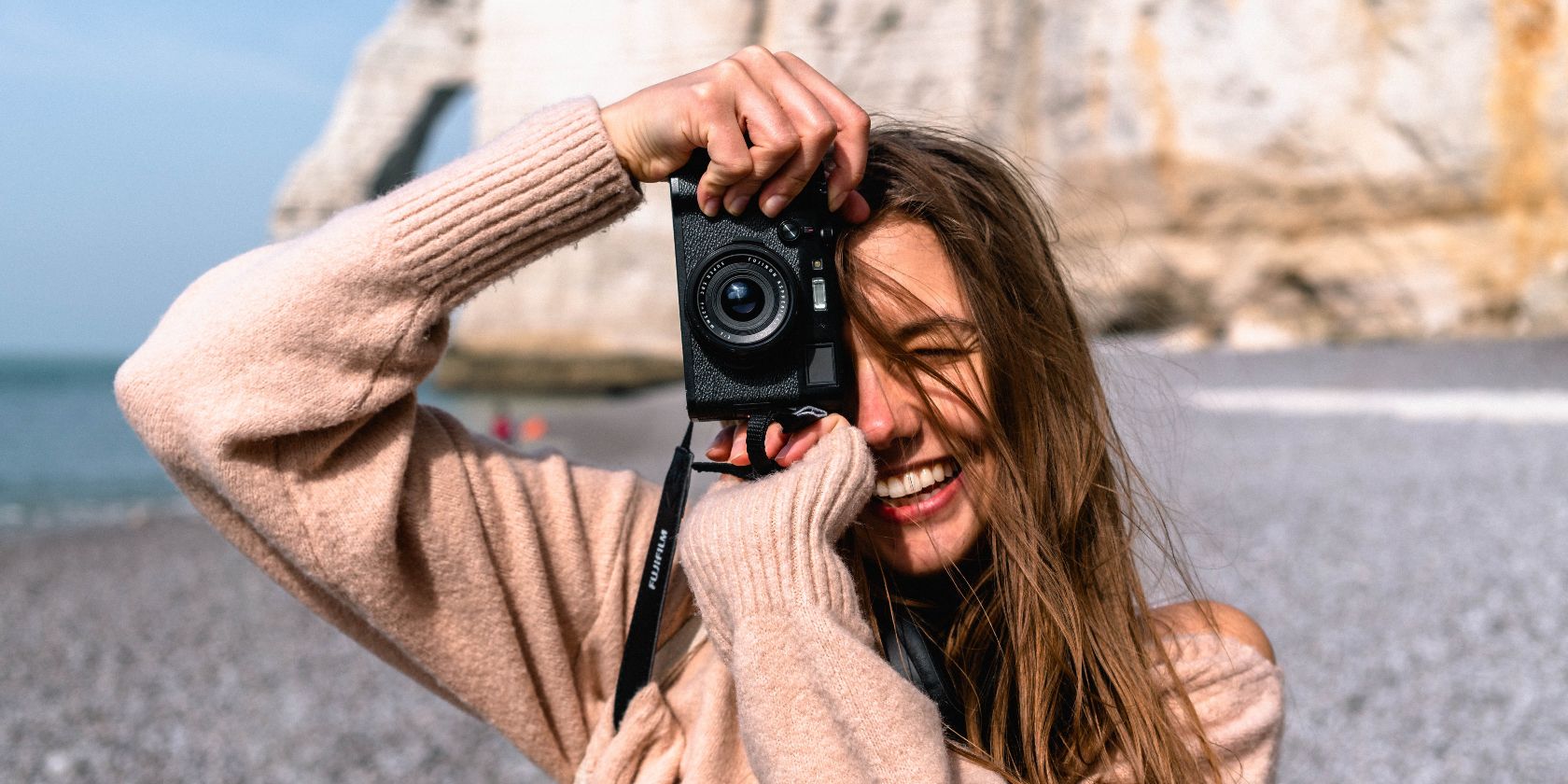 một người phụ nữ cầm máy ảnh và chụp ảnh người khác với một vách đá ở hậu cảnh