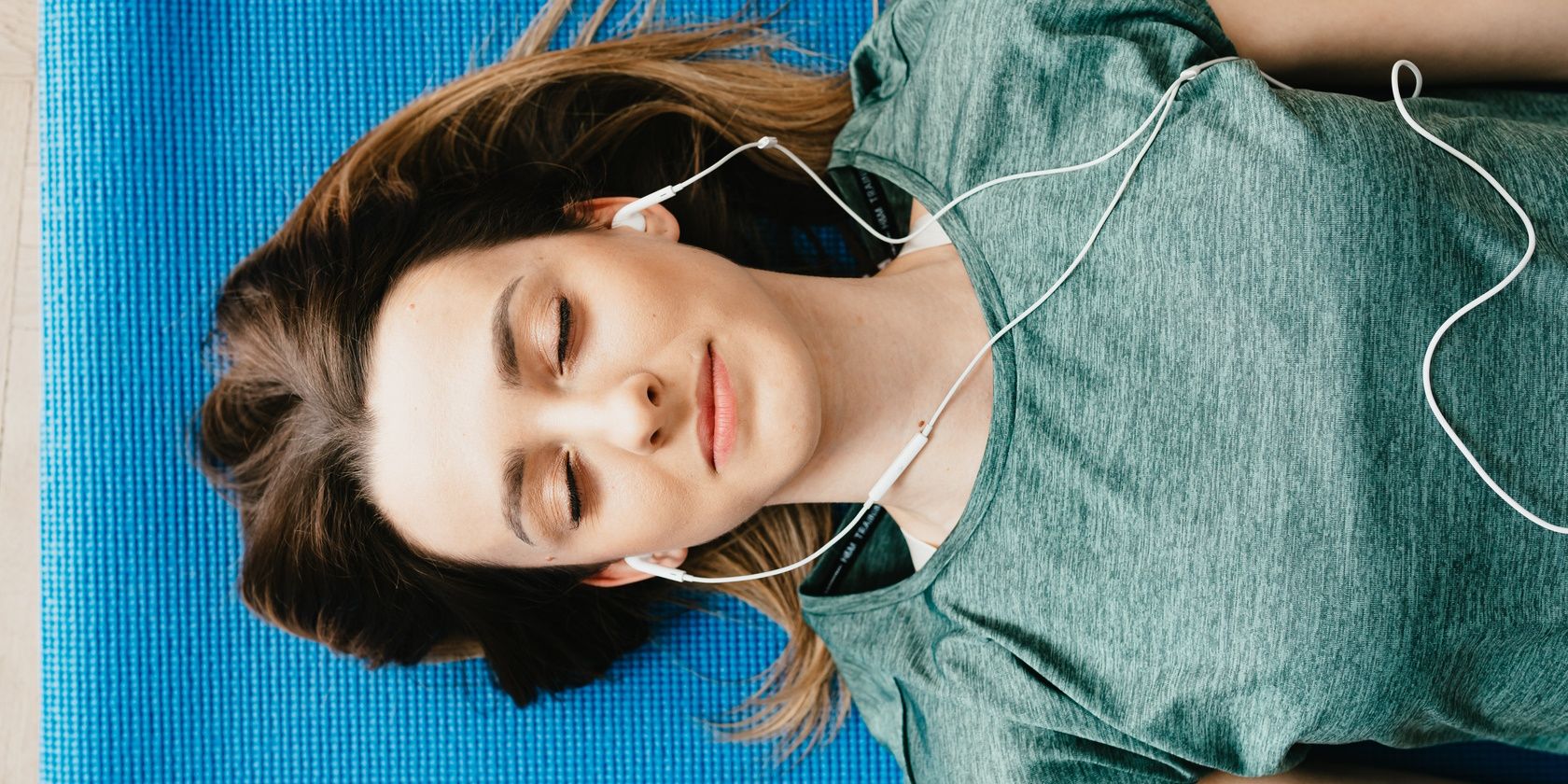 relaxed women wearing earphones and lying down on yoga mat
