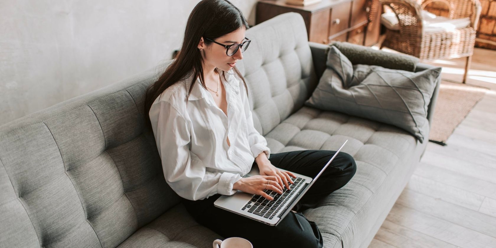 A bespectacled woman typing on a laptop