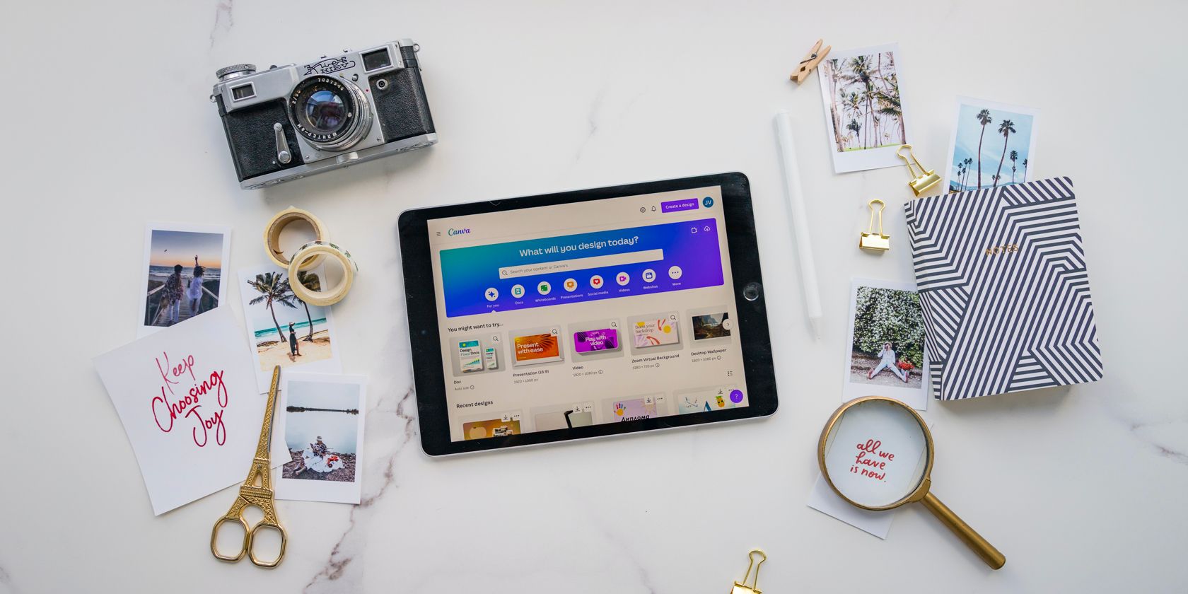 A desk with items for creating a positivity mood board including Canva app on a tablet