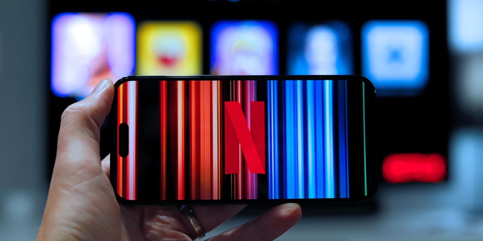 O mână ține un telefon mobil cu sigla Netflix pe ecran