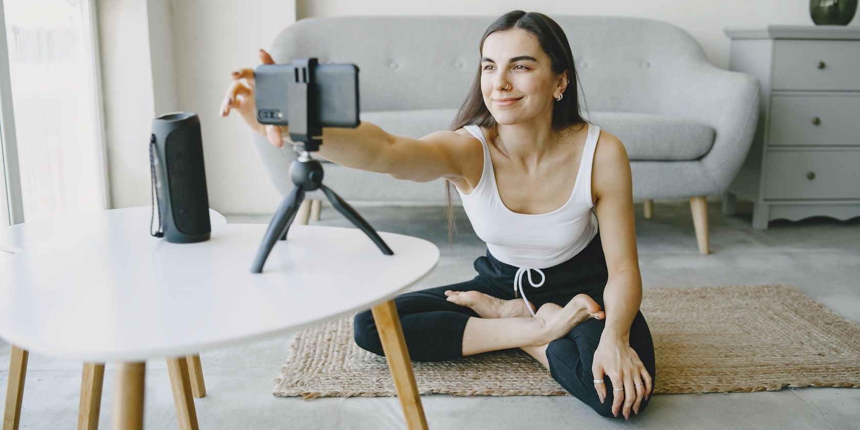 A woman recording herself with a phone and tripod stand