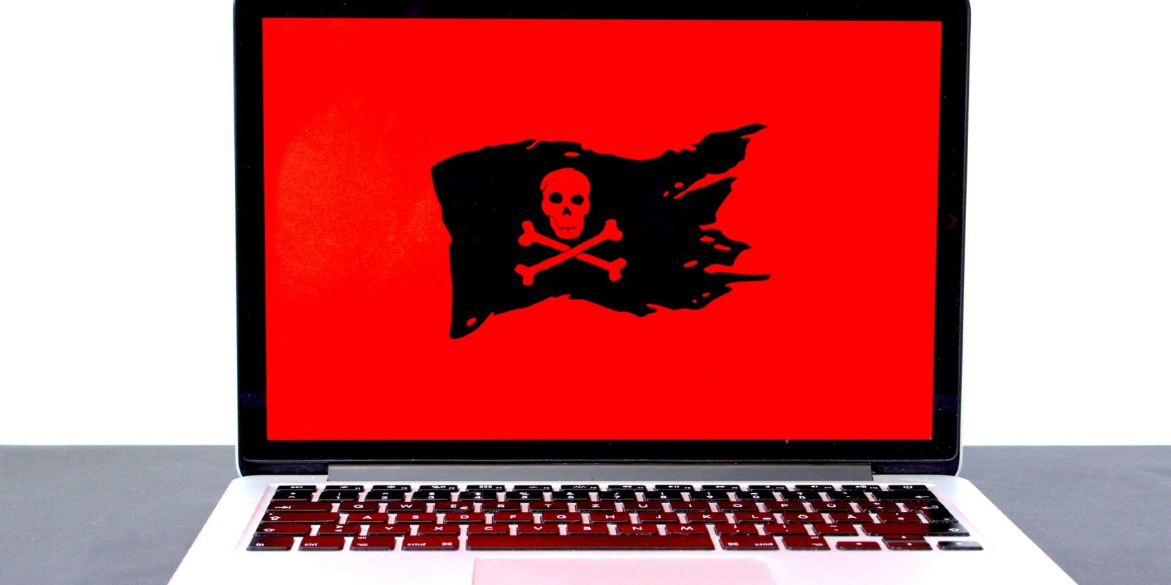 An open laptop with a black pirate flag against a red background on the screen.