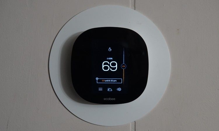 Um termostato inteligente ecobee preto montado em uma parede.