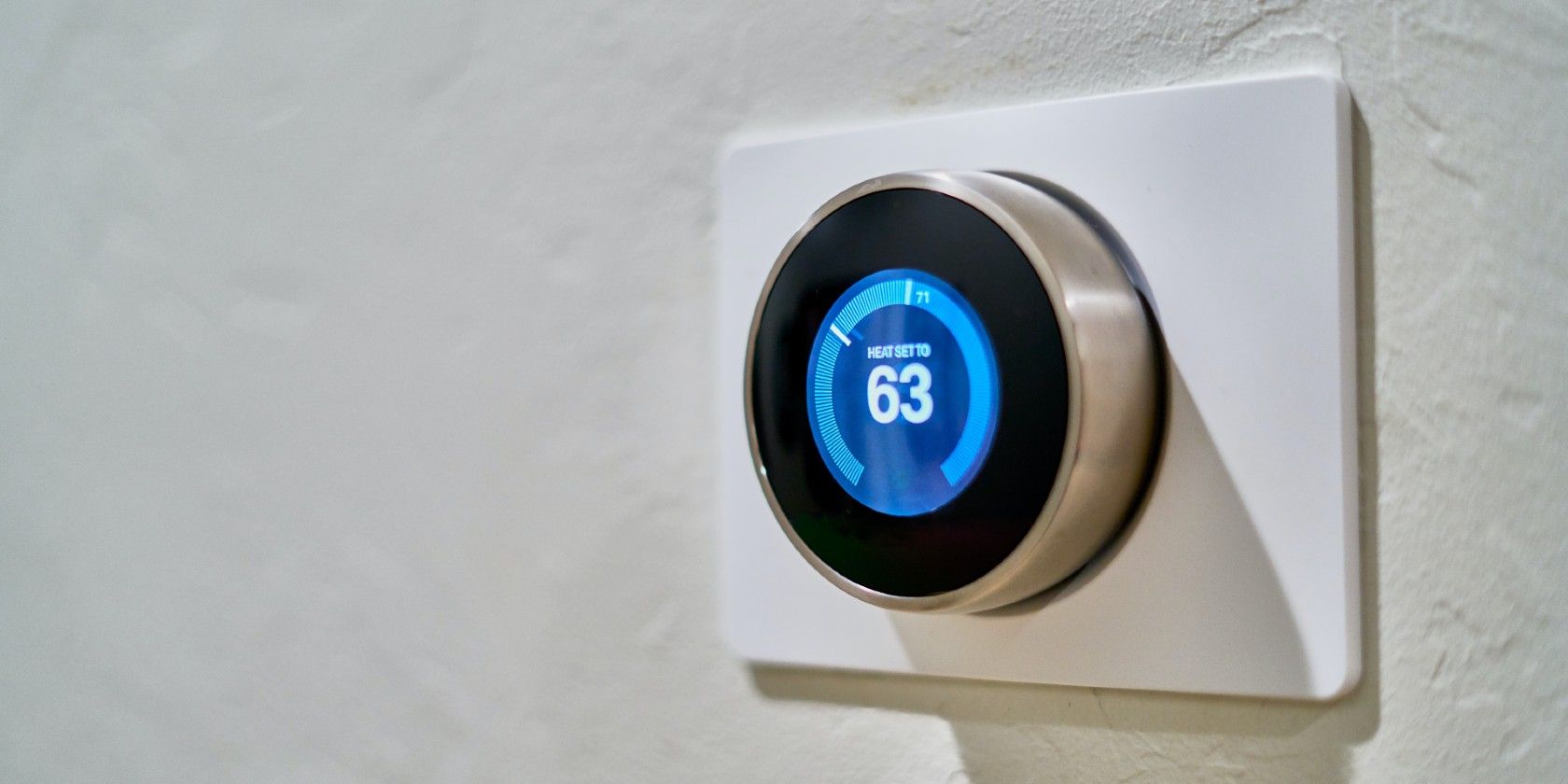 A gray Nest thermostat mounted on the wall showing the temperature.