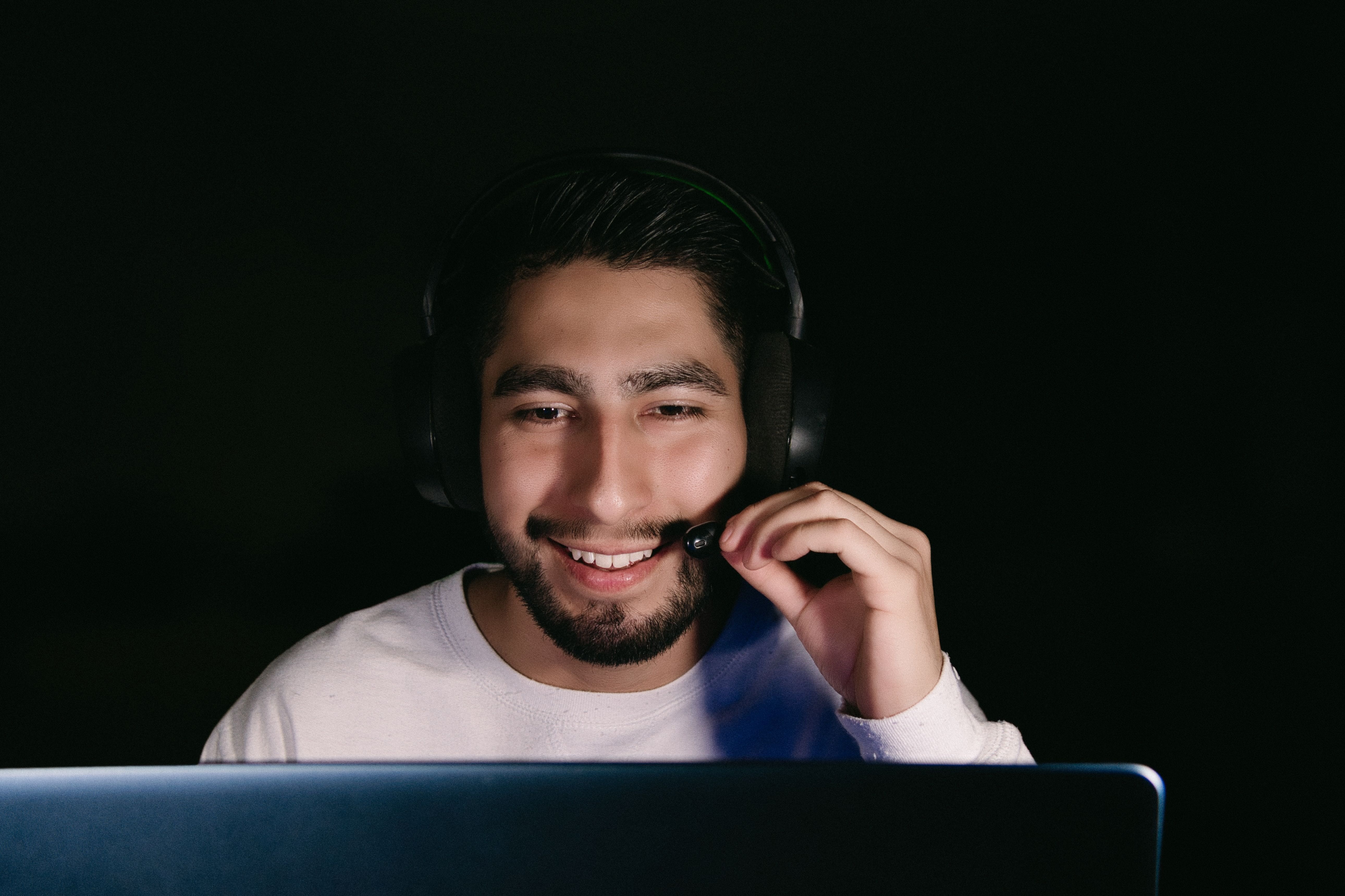 Homme tenant un casque d'écoute et regardant l'écran d'un ordinateur portable