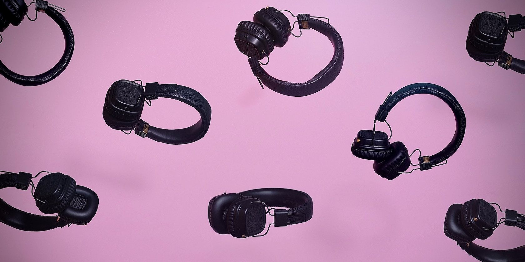 Repeating image of black headphones laid on a purple backgroud