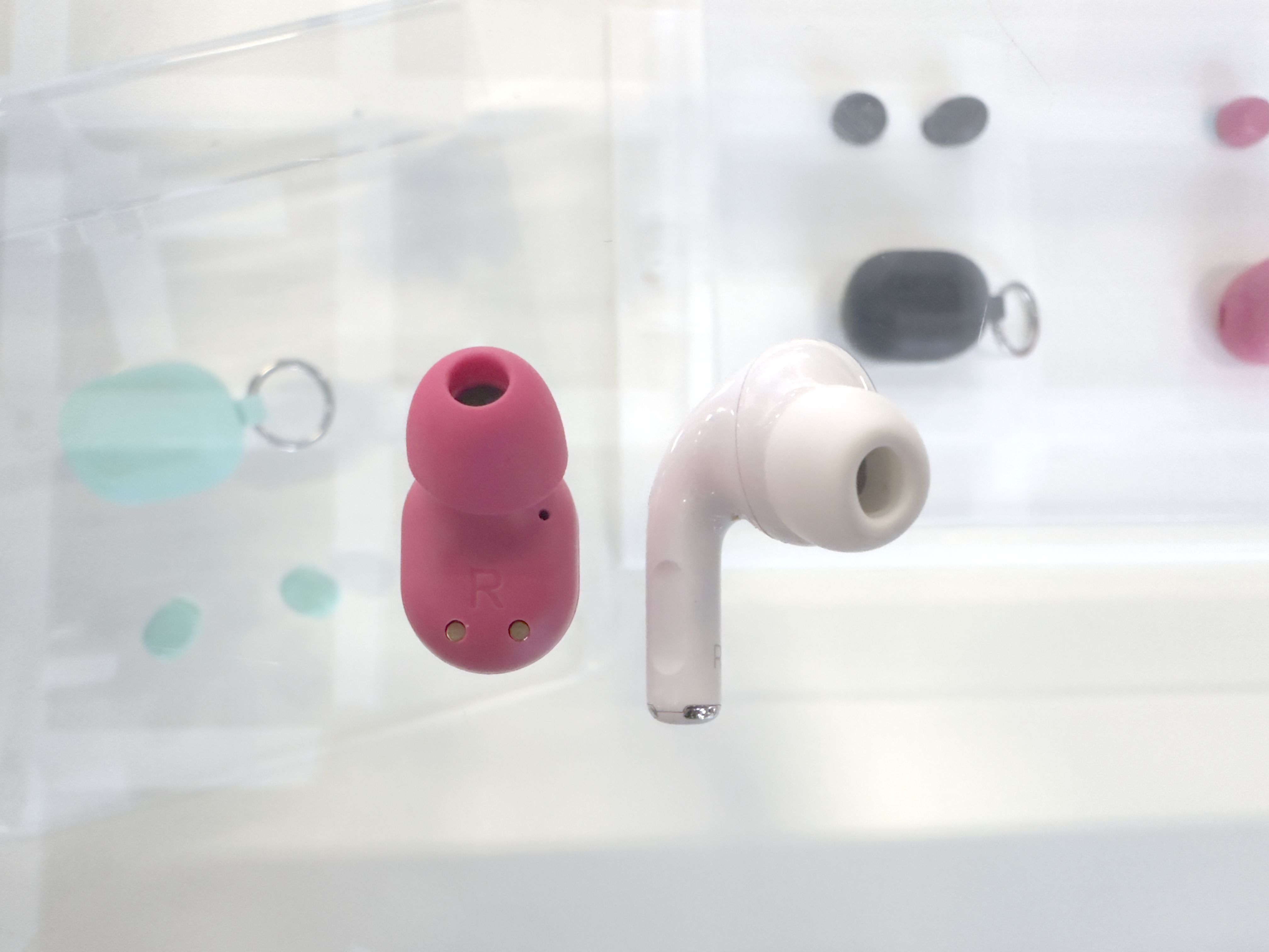 تصویری از earbuds Mini Jbuds در کنار هدفون AirPod برای مقایسه