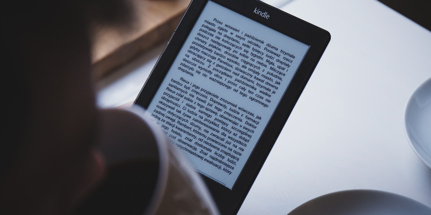 Person Using A Kindle While Reading Coffee