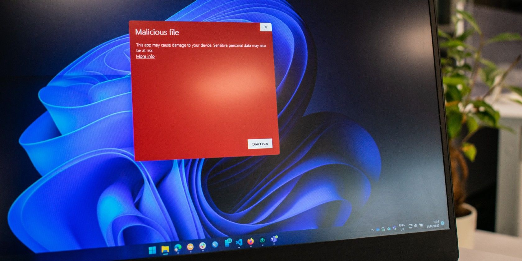 A laptop screen showing a red malicious file warning popup.