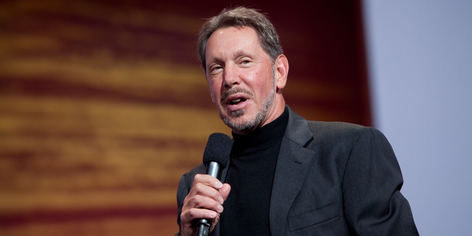 Larry Ellison Speaking on Stage at Event With Microphone