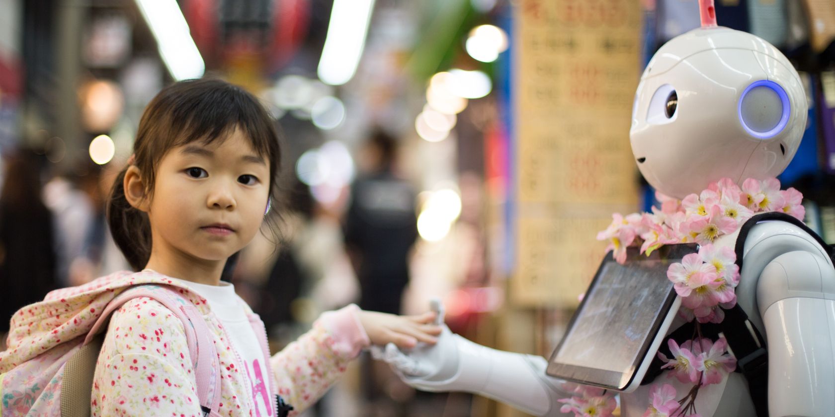 litlte girl holding hands with robot