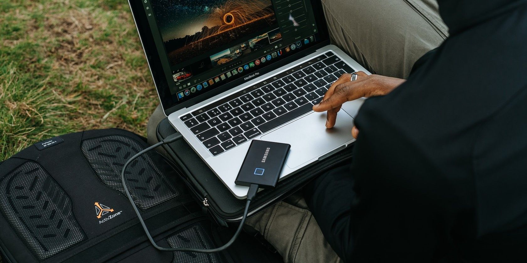 Man outside using a macbook and external SSD