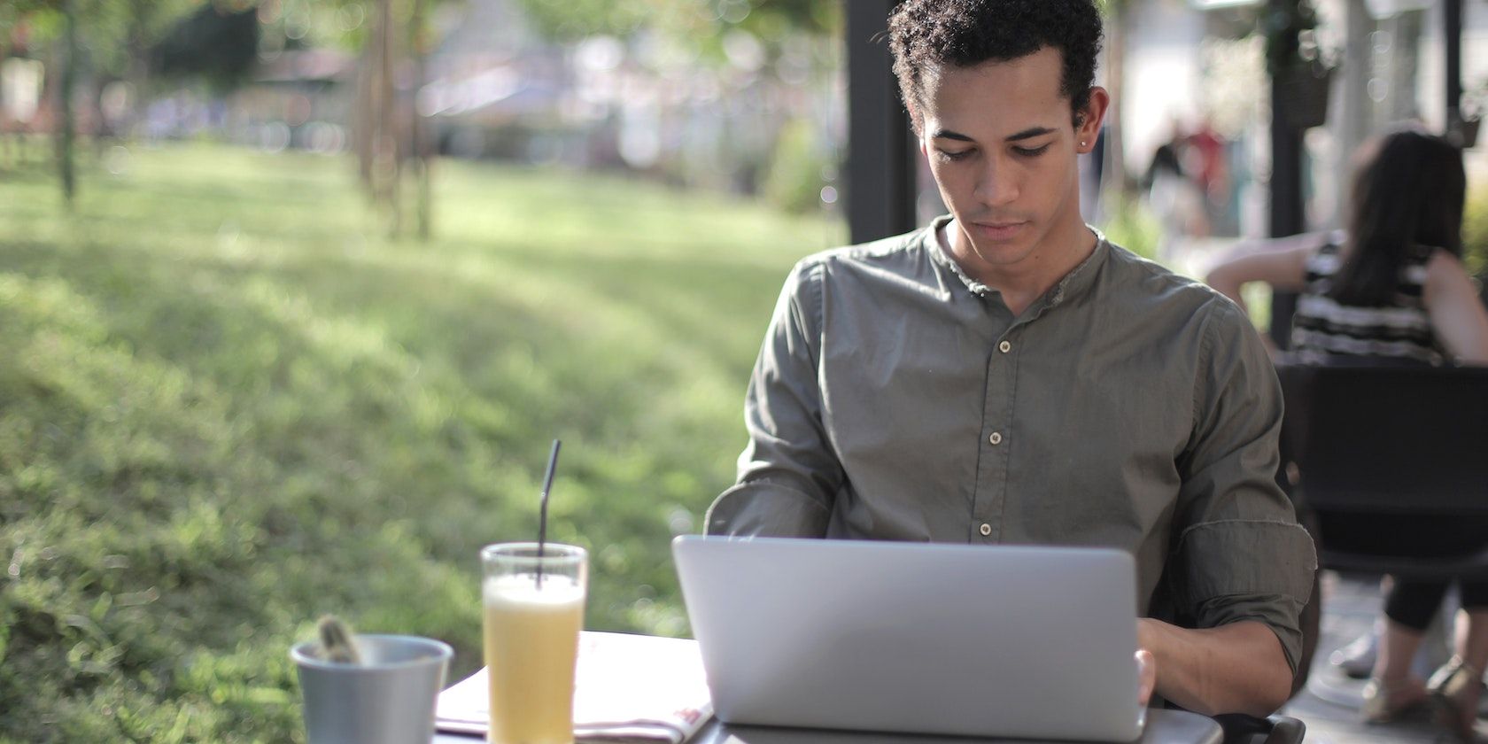Man sitting at a street cafe focused on laptop screen