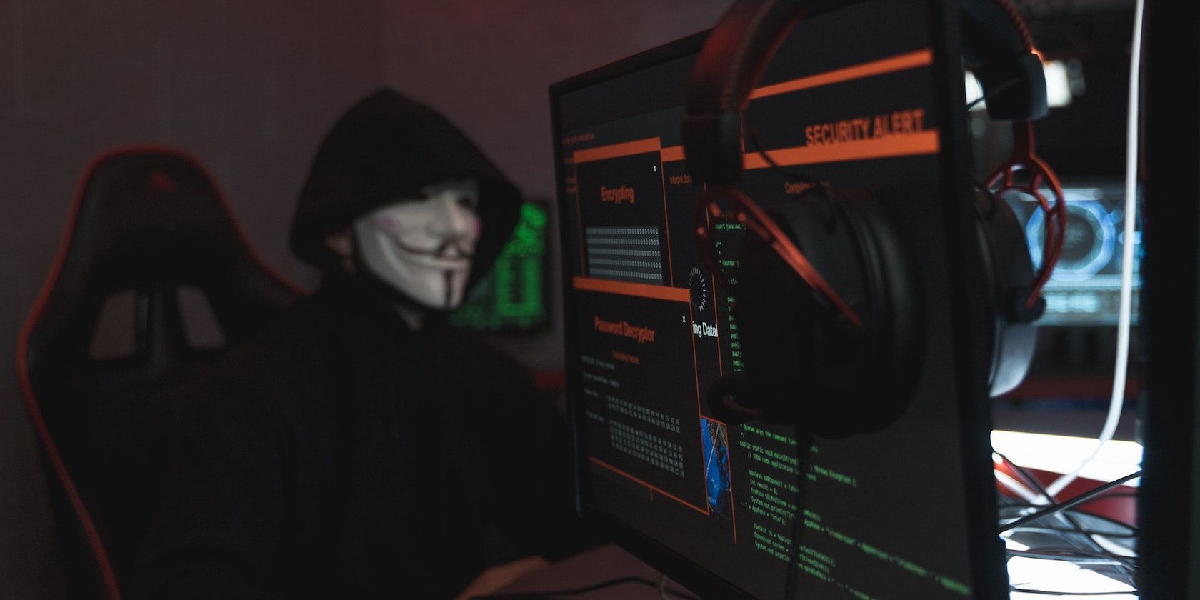 Masked man in front of laptop screen