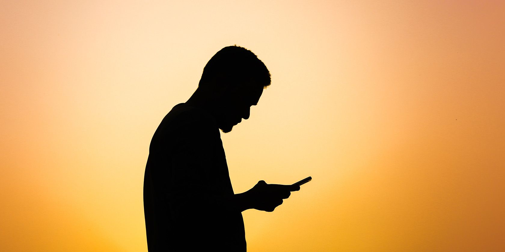 Person using phone silhouetted by sunlight