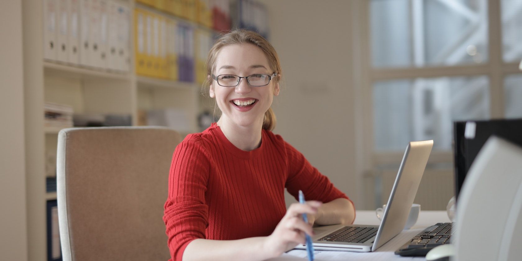 woman smiles while typing on laptop