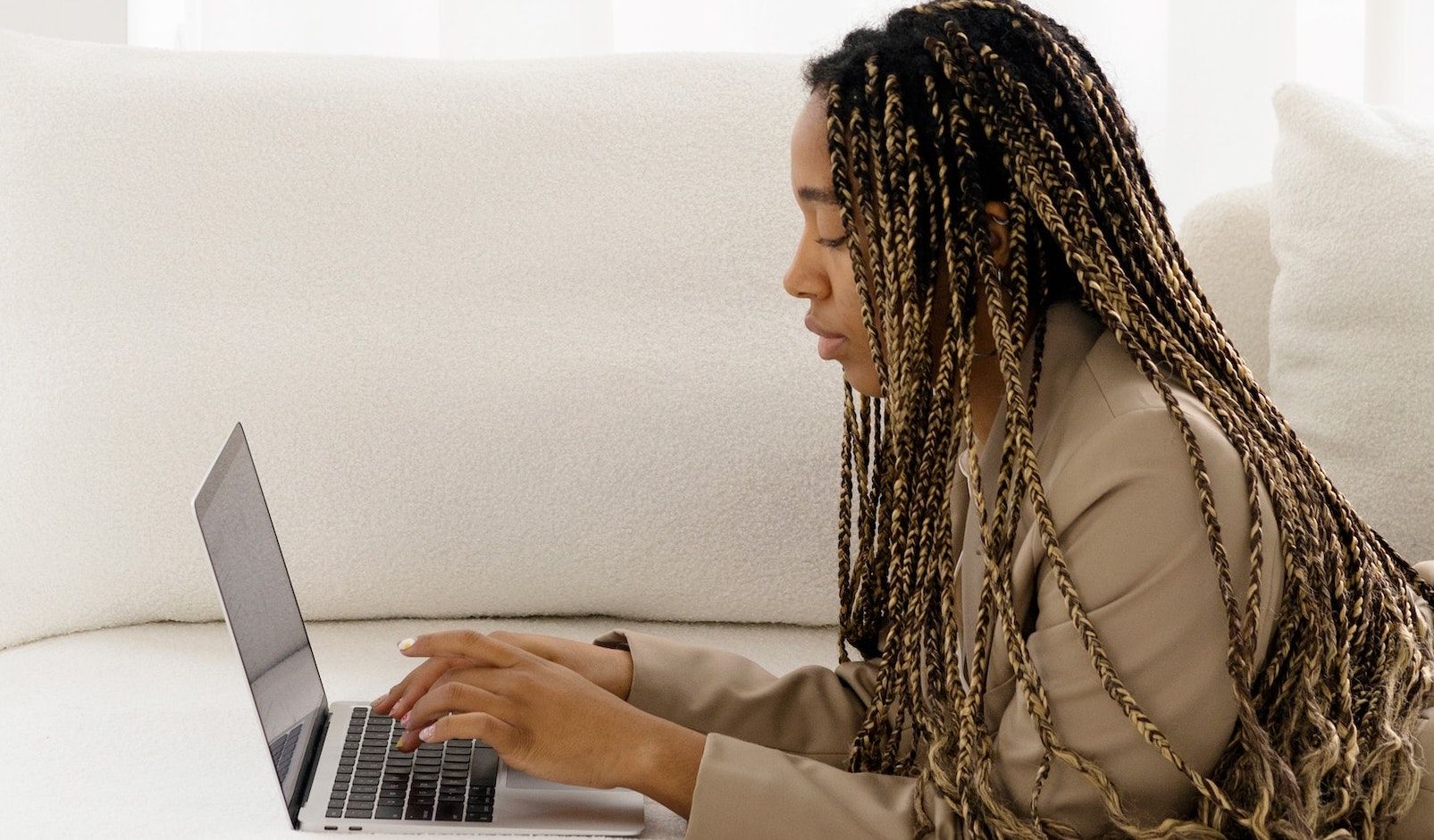 Mulher trabalhando em um laptop no sofá
