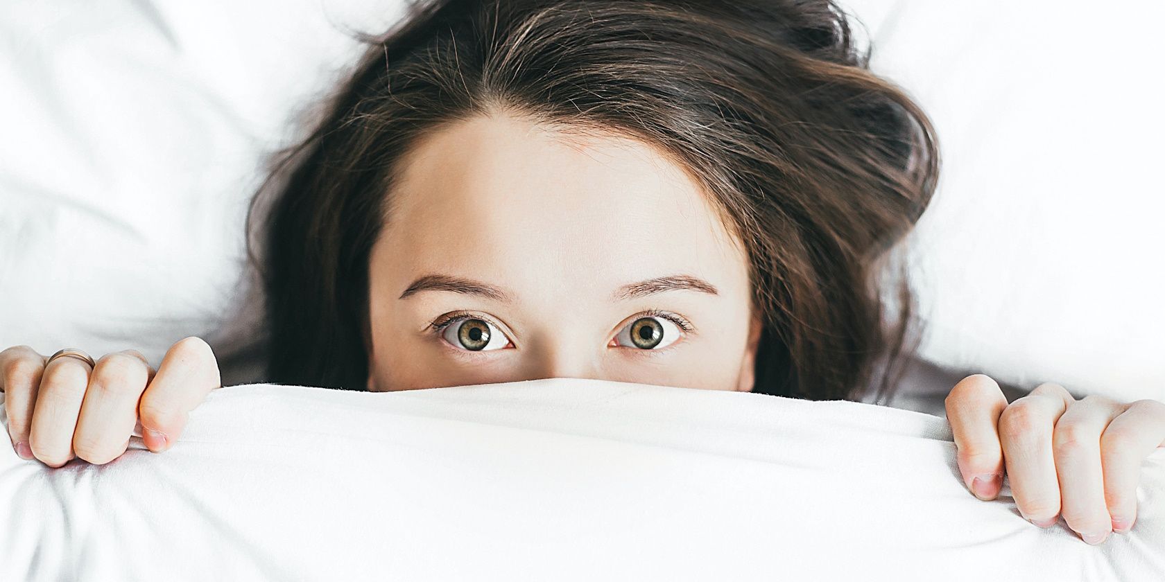 woman in bed covered face with blanket