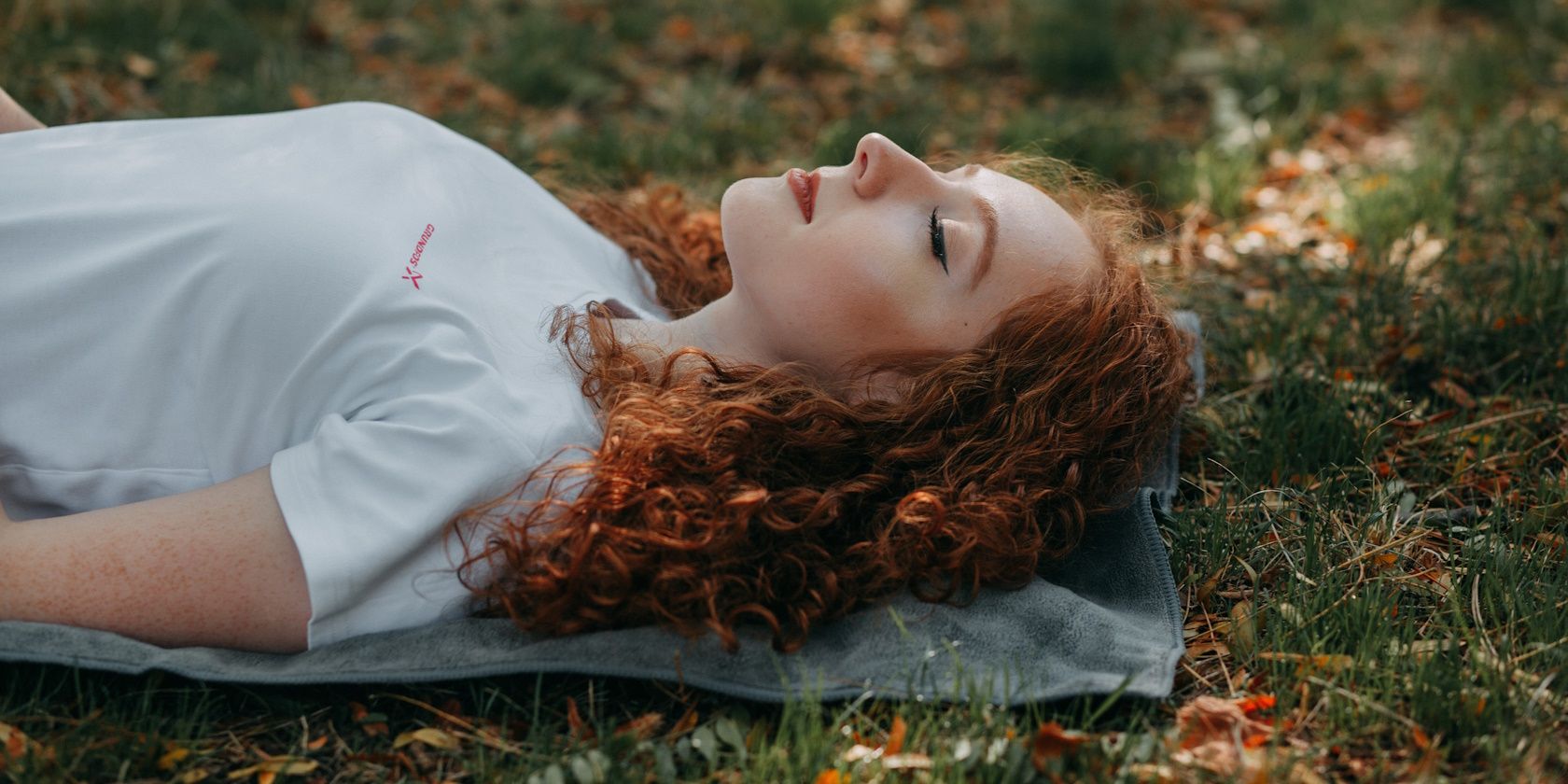 red-haired woman lying outside on grass